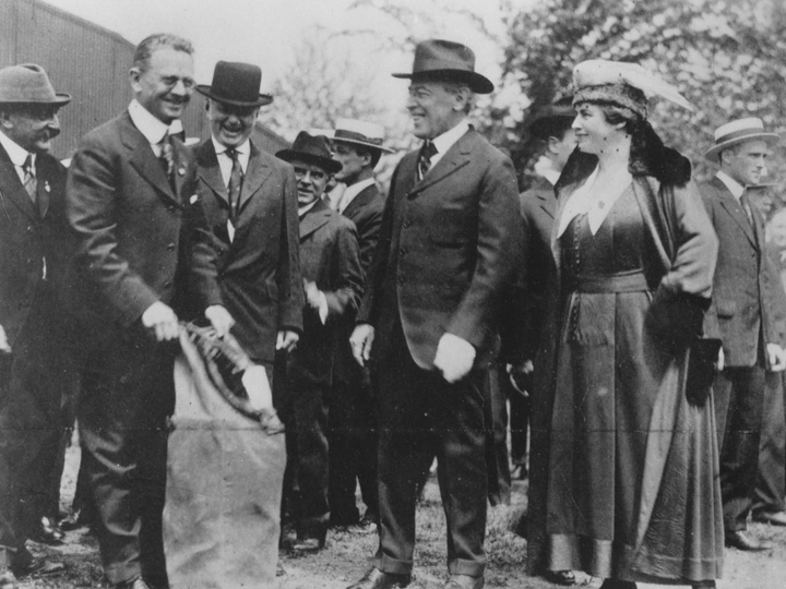 Washington's postmaster, Merritt O. Chance, holding mailbag while President Wilson and dignitaries await Lieutenant Boyle's take off on May 15, 1918
