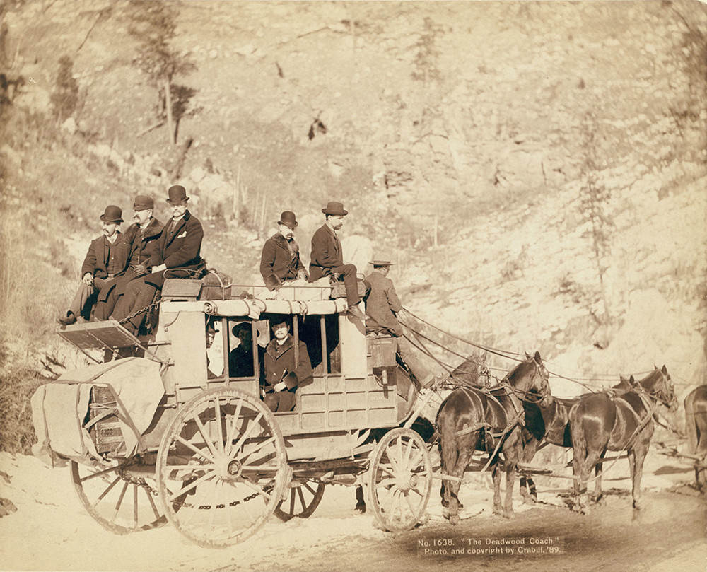 Side view of a stagecoach; formally dressed men sitting in and on top of coach.
