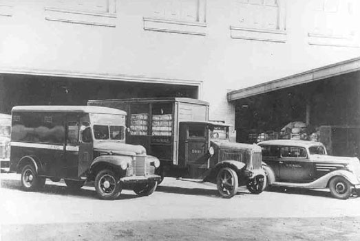 black and white photo of three various mail trucks