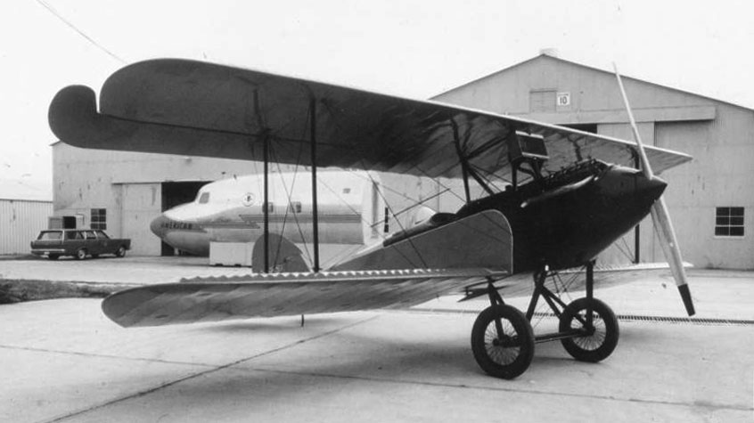 The Waco 9, a small biplane, sits in front of the Paul E. Garber facilities storage for Air and Space.The plane is facing to the right on its own two wheels.