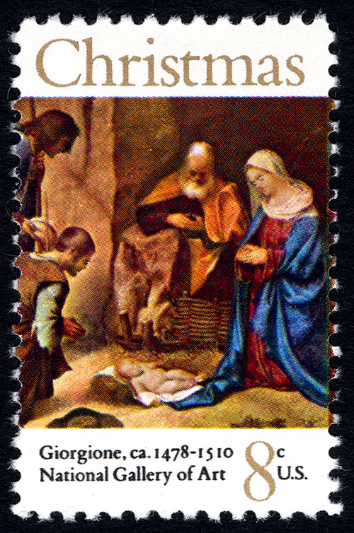 Postage stamp of four people gathered in a landscape, their heads bowed down towards an infant who lays on a white cloth on the ground.
