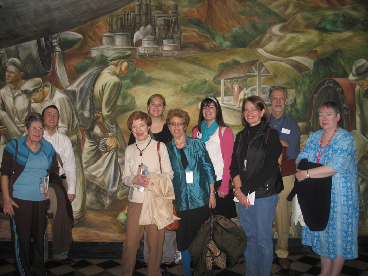 Museum docents and staff pose in front of a mural