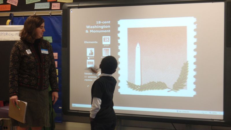 A student and a museum educator use a large screen to view materials