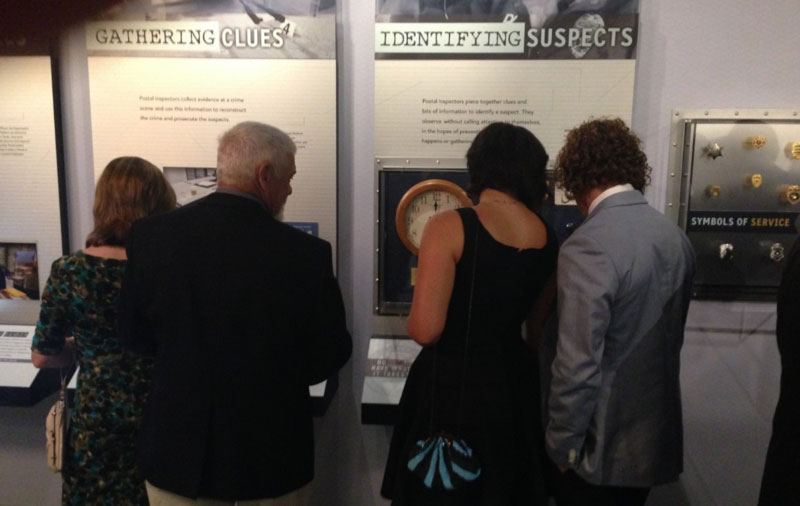 Four people looking at objects in an exhibit display