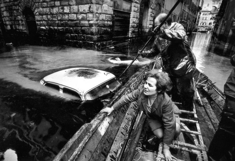 A man and woman in a boat in a flooded street