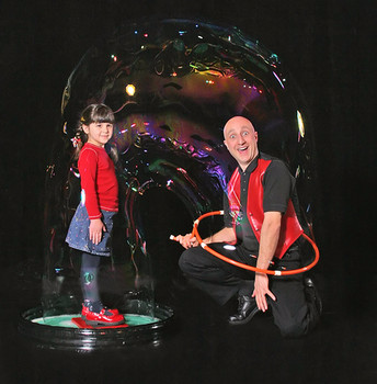 A man and girl posing inside a large bubble created with soap