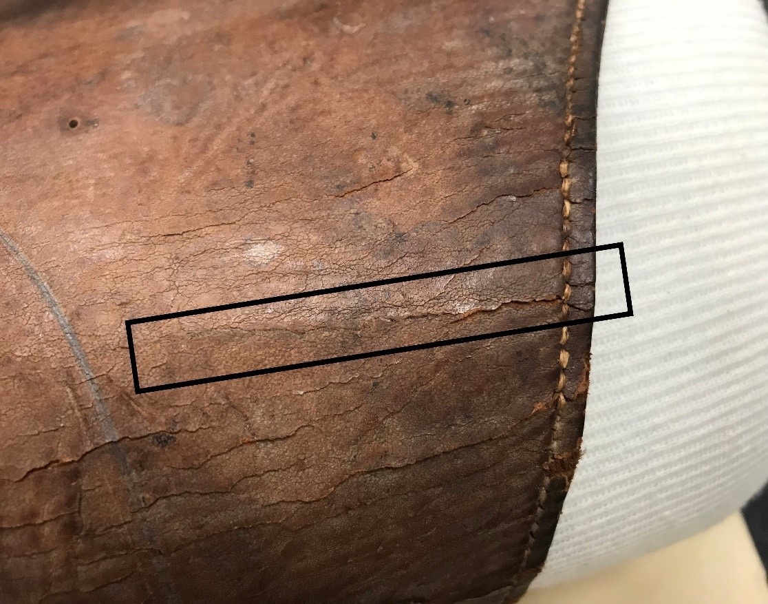 Close up photograph of cracks in the leather straps of the bag.