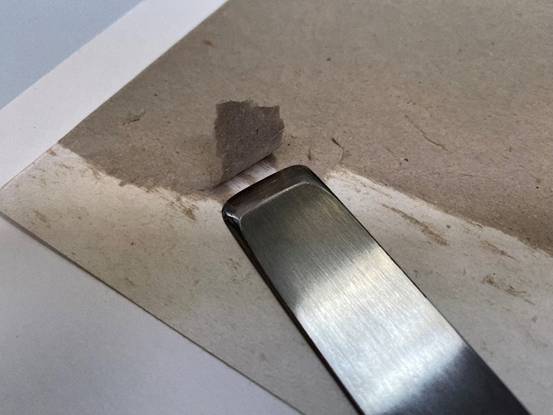 someone carefully removing stamp art board backing with a small knife