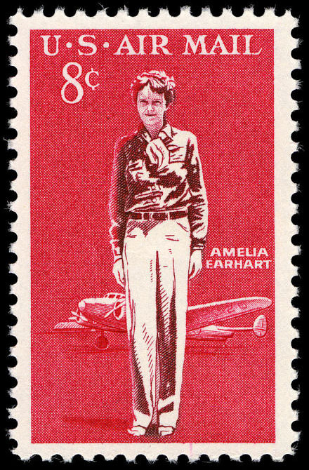 postage stamp featuring an illustration of Amelia Earhart standing with a plane in the background