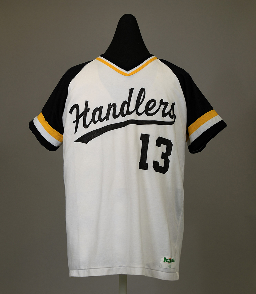 Front of T-shirt with softball team name and player number at center, “Handlers 13,” and manufacturer’s label on lower right