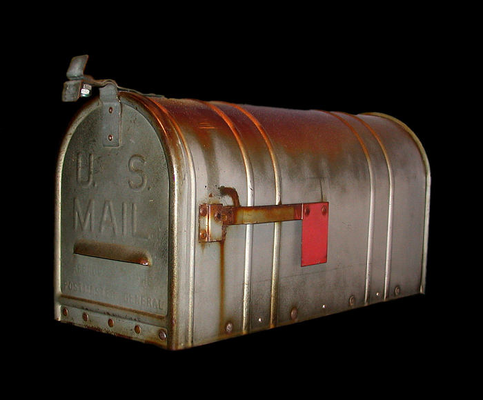 a tunnel-shaped mailbox with a red signal flag