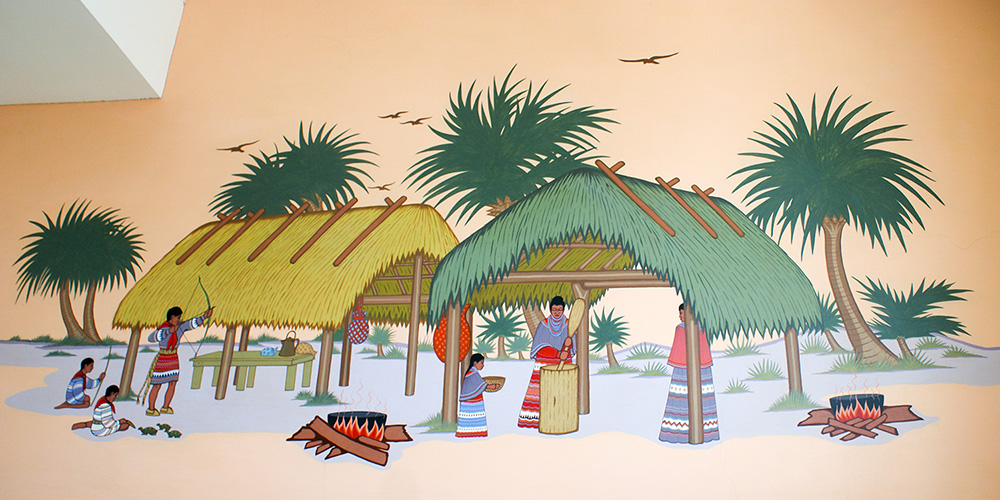Painting of six indians working while sitting and standing surrounded by shelters and palm trees.