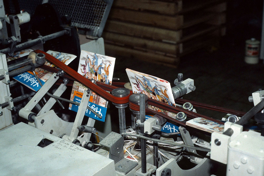 Highlights magazines are trimmed and then moved onto a conveyor that flips them into the proper position for mailing labels.