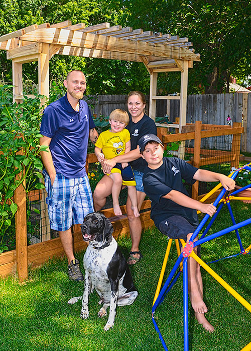 Parents and two children with dog playing in a back yard