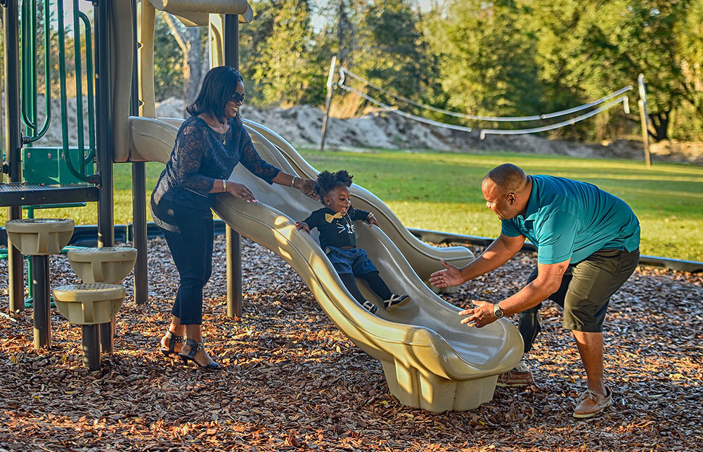 Parents and child playing on a slide in a playground